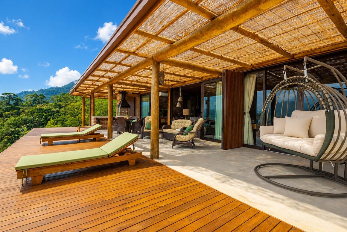 Varanda com deck de madeira, pergolado de bambu e vista para a serra